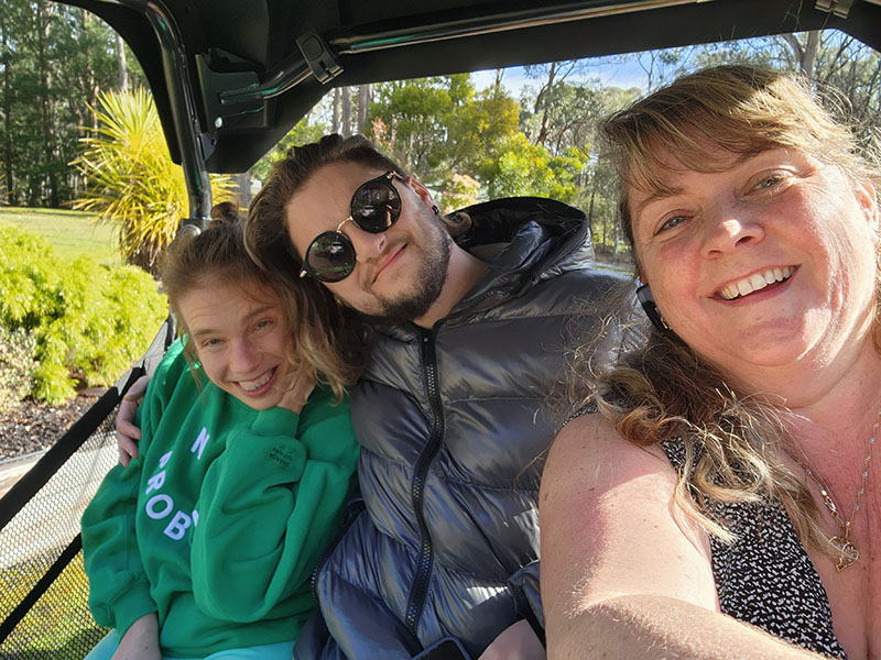 Three people sitting in a vehicle smiling for the camera
