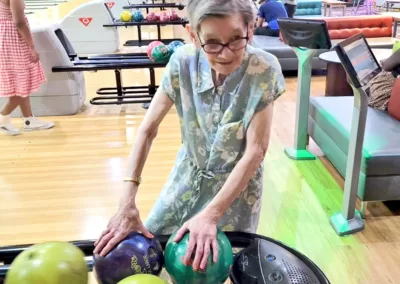 An elderly woman chooses the ball she’ll use at tenpin bowling