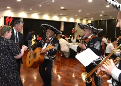 A three-piece mariachi band plays to a dancing man and woman.