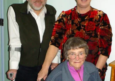 A middle-aged man and woman stand behind a seated older woman.