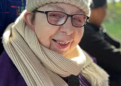 A woman in scarf and beanie smiles for the camera