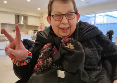 A smiling woman gives the V for Victory sign with her hand.