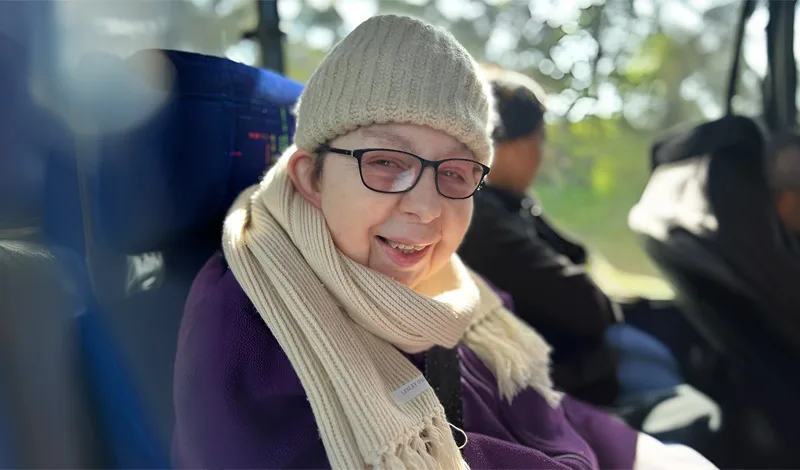 A woman in scarf and beanie smiles for the camera