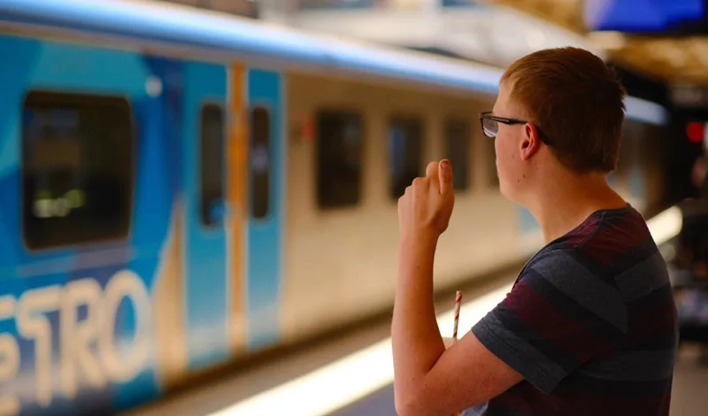 A man in profile waves as a suburban train passes