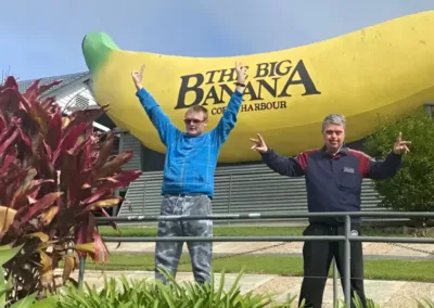 Two men stand with arms raised in front of the Coffs Harbour Big Banana