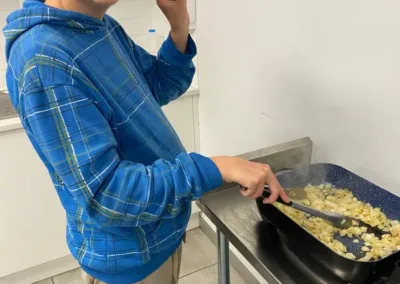 A man raises his hand as he cooks dinner in a frypan