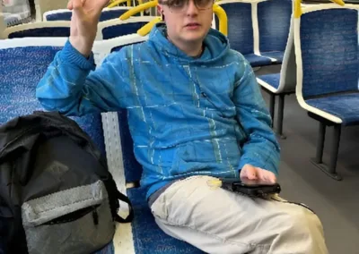 A man waves as he sits in a train carriage.