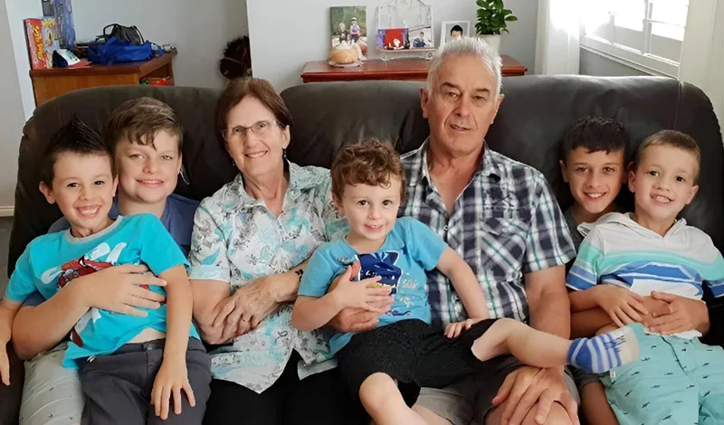 Parents and five children sit on a couch